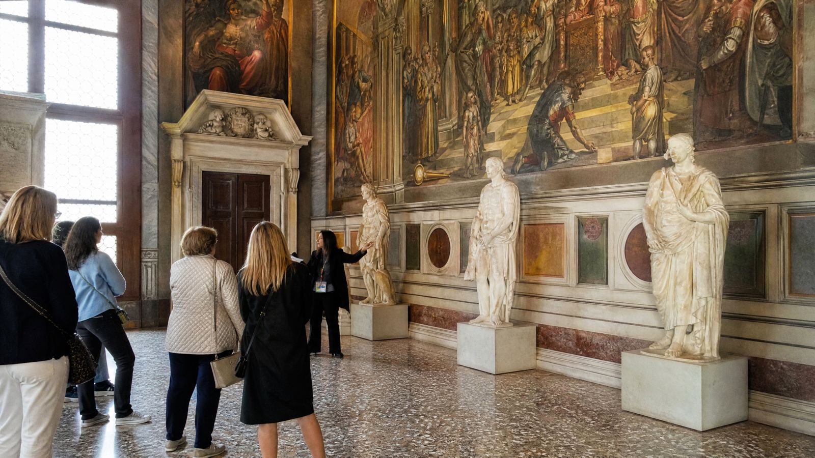Visitors with a guide in a frescoed Venetian palace hall